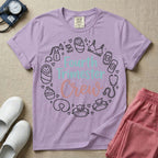 A postpartum nursing t-shirt featuring the stacked text "Fourth Trimester Crew" in blue and pink retro fonts, surrounded by a circular border of white minimalist line drawings depicting newborn and postpartum care items including a breast pump, swaddled baby, maternity bra, maxi pad, stethoscope, wipes, and a nursing pillow.