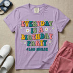 A retro graphic tee for labor and delivery nurses featuring bubble lettering that reads "EVERYDAY IS A BIRTHDAY PARTY #L&D NURSE" surrounded by small daisies and stars.