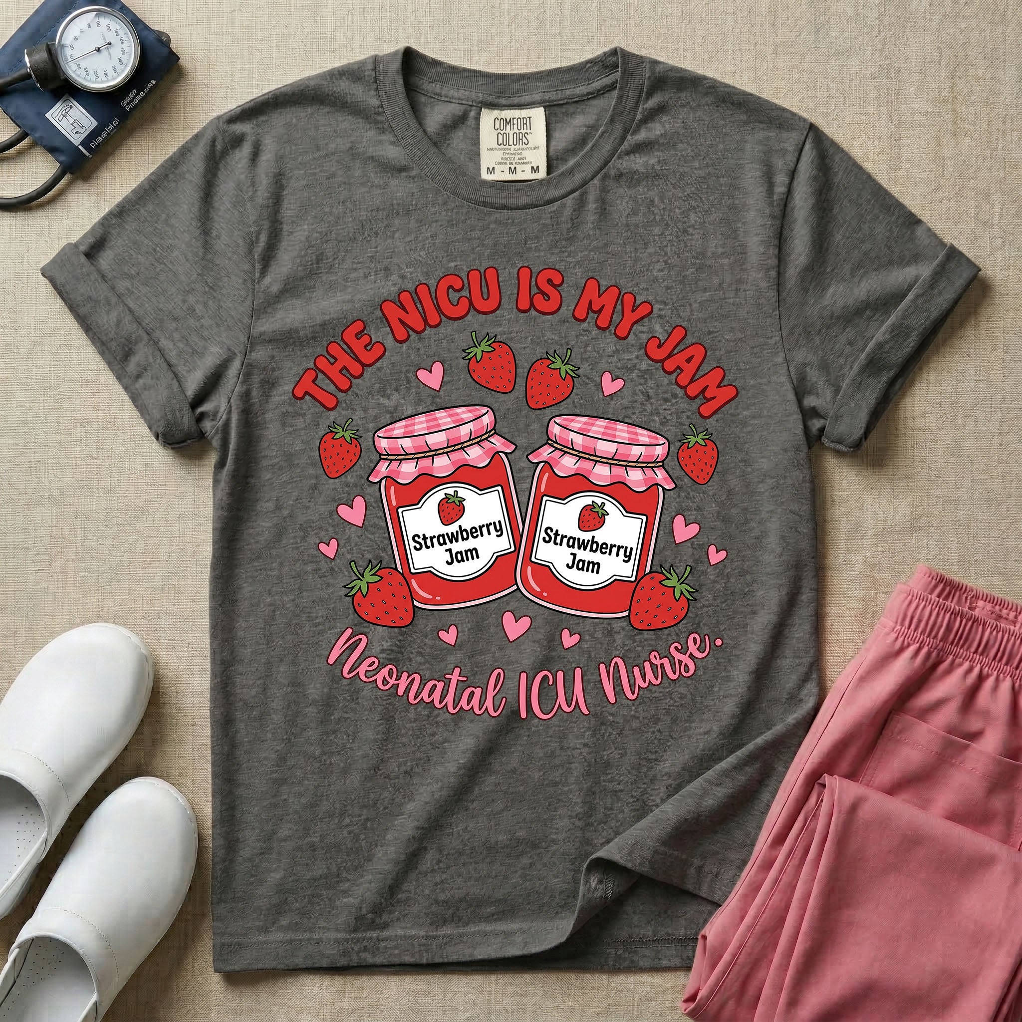 A t-shirt featuring two jars of strawberry jam surrounded by small hearts and strawberries with the text THE NICU IS MY JAM arched above and Neonatal ICU Nurse written in a retro script below.