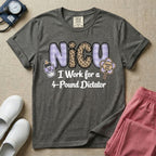 A funny t-shirt for NICU nurses featuring the text "NICU I Work for a 4-Pound Dictator" designed with purple plaid and leopard print letters, accompanied by graphics of a baby bottle with a bow and a rattle that says "WARNING: TINY BOSS".