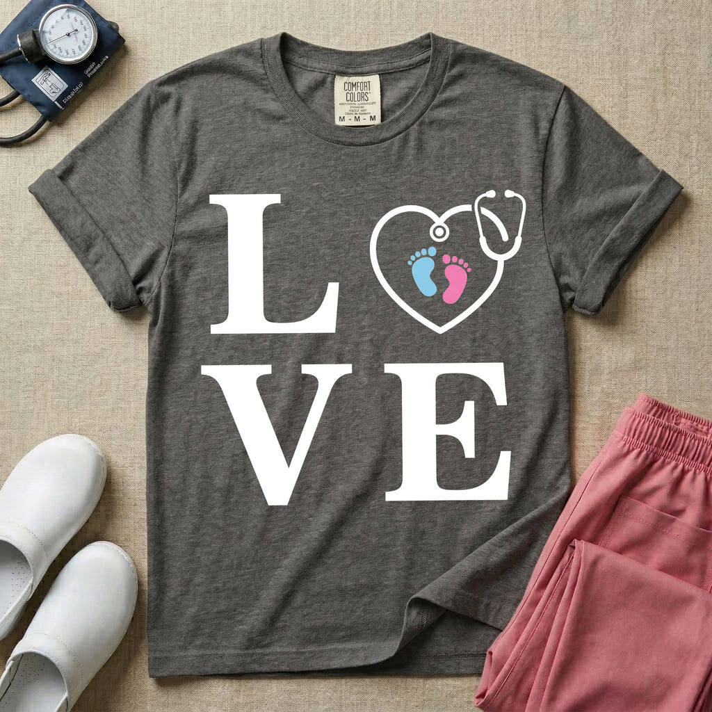 A minimalist nursing t-shirt featuring the word LOVE stacked in large white serif letters, with the letter O replaced by a white stethoscope shaped like a heart containing two small baby footprints, one pink and one blue.