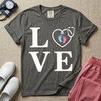 A minimalist nursing t-shirt featuring the word LOVE stacked in large white serif letters, with the letter O replaced by a white stethoscope shaped like a heart containing two small baby footprints, one pink and one blue.