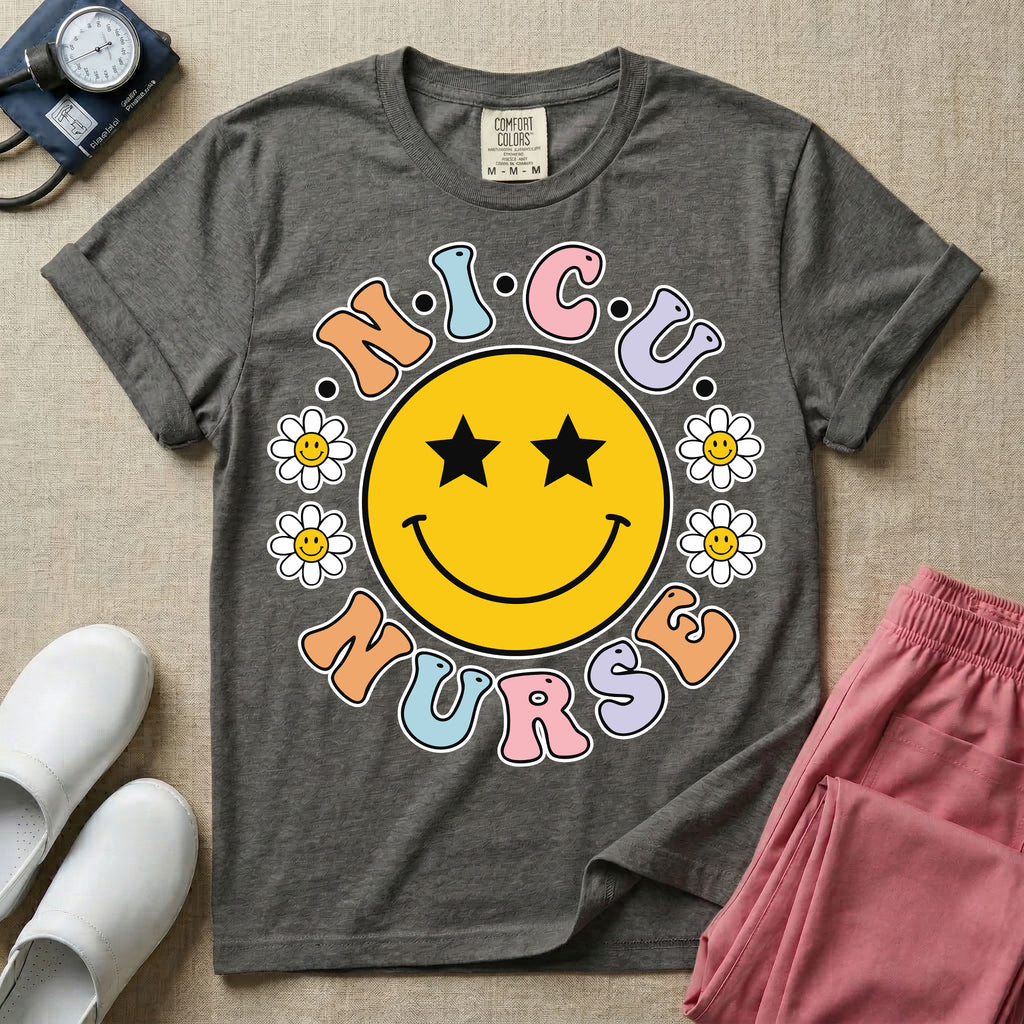 A t-shirt featuring a large yellow smiley face with star eyes surrounded by smiley face daisies and the text N.I.C.U. NURSE in pastel retro bubble lettering.