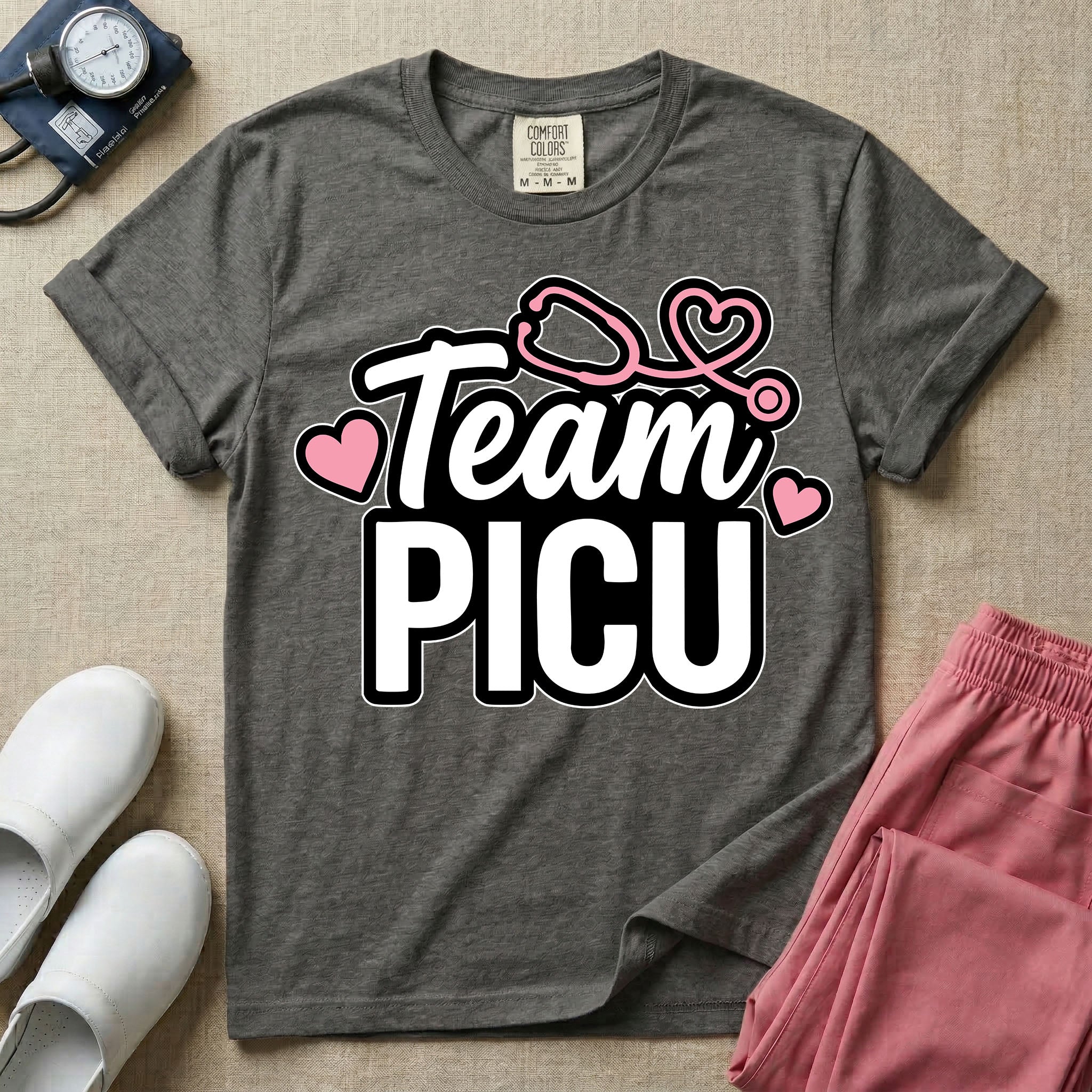 A descriptive graphic tee for pediatric intensive care nurses featuring the text "Team PICU" in bold white lettering, accented with pink hearts and a pink stethoscope design.