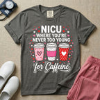A Valentine's Day themed graphic for a Neonatal Intensive Care Unit featuring the text 'NICU WHERE YOU'RE NEVER TOO YOUNG' stacked above three to-go coffee cups decorated with heart patterns, with 'for Caffeine' written in script at the bottom, all surrounded by small red and pink hearts.