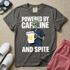 A humorous graphic for general nursing featuring an illustration of a skeleton wearing a green scrub cap and dark blue scrubs, holding a large white coffee cup with a yellow biohazard symbol, with the stacked text 'POWERED BY CAFFEINE' above it and 'AND SPITE' below it.