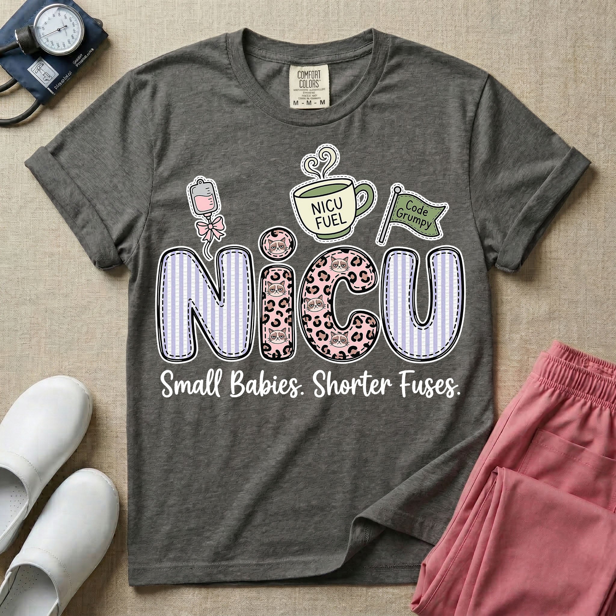 A funny t-shirt for NICU nurses featuring the large text "NICU" patterned with purple stripes and pink leopard print containing grumpy cat faces, accompanied by graphics of an IV bag with a pink bow, a steaming coffee cup reading "NICU FUEL", a green flag saying "Code Grumpy", and the bottom text "Small Babies. Shorter Fuses."