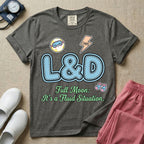 A humorous Labor and Delivery nurse graphic featuring large, light blue varsity-style letters spelling L&D with a pink dashed outline, surrounded by small patch-like icons of a baby and a lightning bolt, sitting above cursive text that reads Full Moon: It's a Fluid Situation.