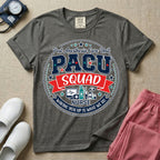 A t-shirt featuring a circular badge design with the text PACU SQUAD in block letters, medical icons like a heart monitor and stethoscope, and the phrase Waking You Up Is What We Do.