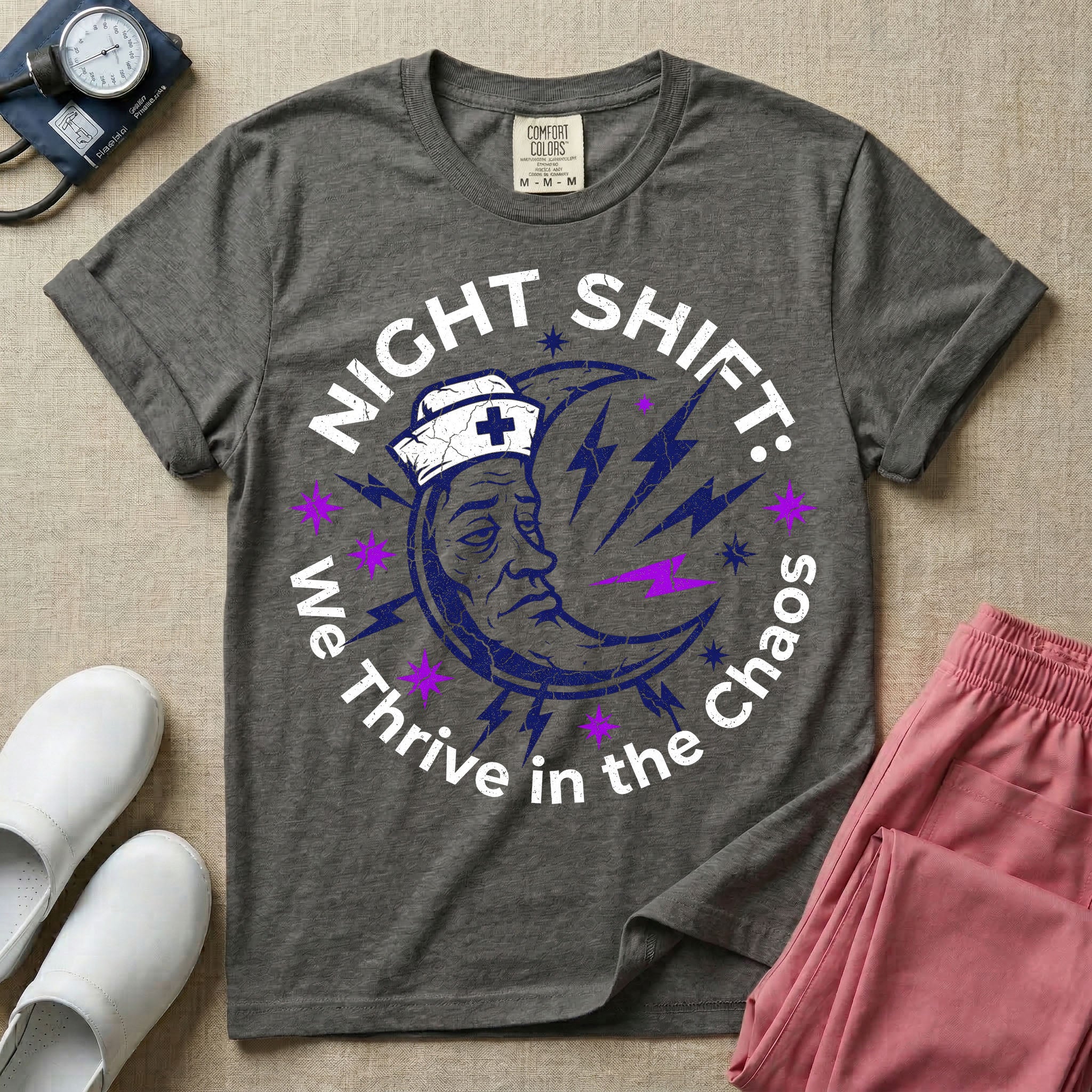 General nursing night shift nurse t-shirt with a retro purple moon wearing a nurse cap and we thrive in the chaos graphic in pepper color.
