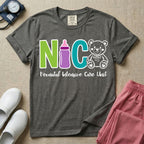 A t-shirt featuring the acronym NICU creatively spelled out using a green letter N, a purple baby bottle, a teal letter C, and a white outlined teddy bear, with the words Neonatal Intensive Care Unit written in cursive script below.