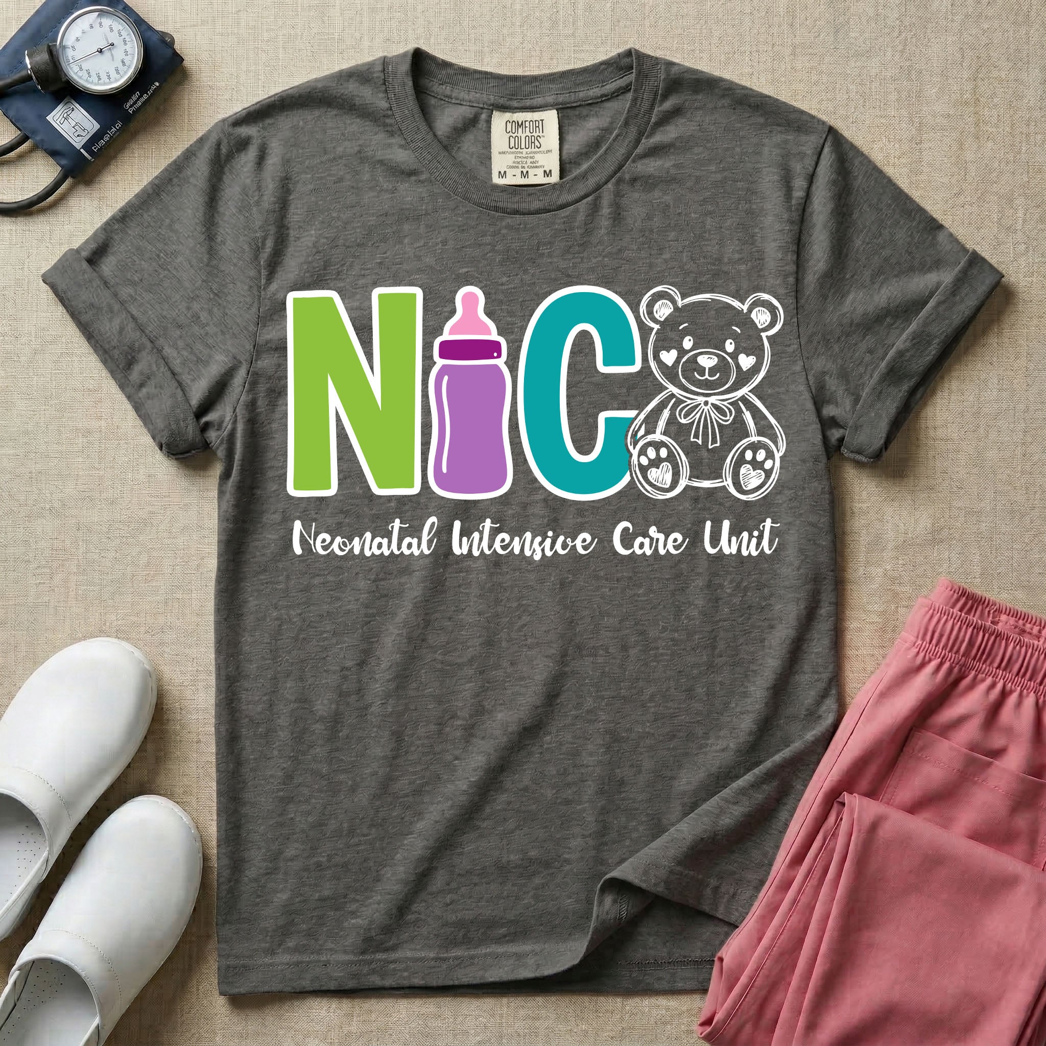 A t-shirt featuring the acronym NICU creatively spelled out using a green letter N, a purple baby bottle, a teal letter C, and a white outlined teddy bear, with the words Neonatal Intensive Care Unit written in cursive script below.