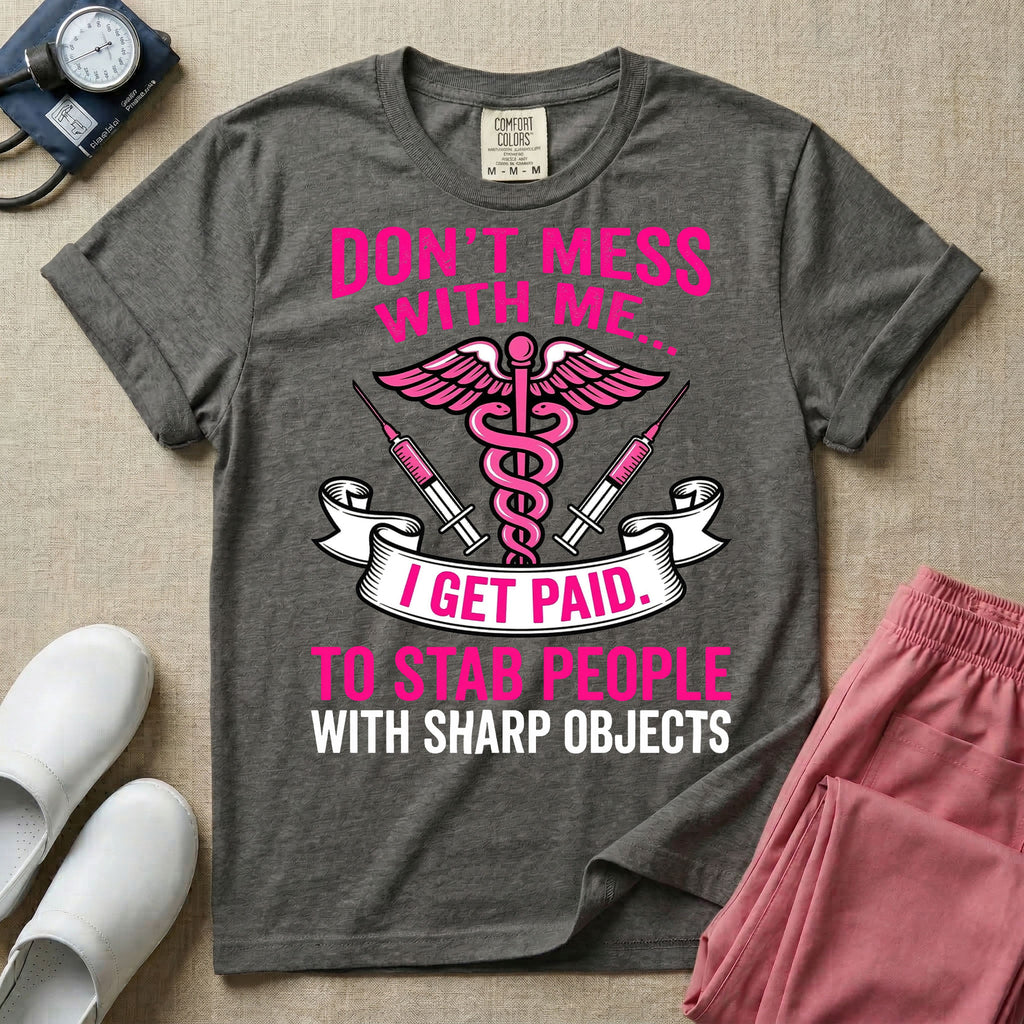 General nursing and ER t-shirt featuring a pink and black caduceus medical symbol flanked by two syringes alongside the humorous text "DON'T MESS WITH ME... I GET PAID TO STAB PEOPLE WITH SHARP OBJECTS".